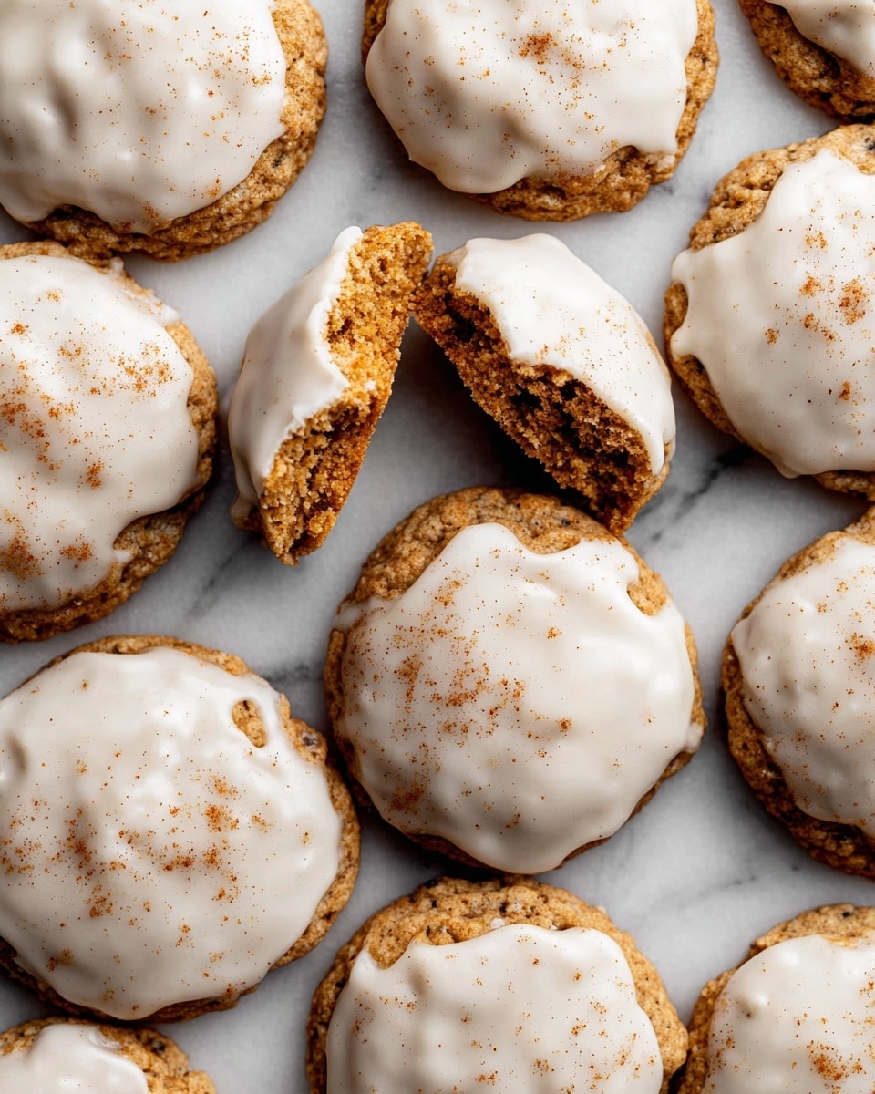 A stack of three thick oatmeal cookies with a light brown color and a rough, crumbly texture sits on a white marbled surface. Each cookie is topped with a smooth, white icing that drips slightly over the edges, adding a glossy contrast. The top cookie has a bite taken out, showing the dense, chewy interior with visible oats. Around the stack, there are more cookies slightly out of focus, emphasizing the main pile in the center. Photo taken with an iphone --ar 4:5 --v 7