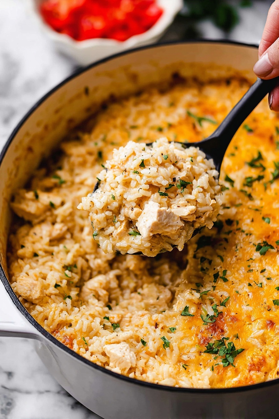 One Pot Queso Chicken and Rice, cheesy chicken and rice dinner, Tex-Mex chicken and rice, quick one pot chicken recipes, easy flavorful weeknight dinner - This image shows a close-up of a white pot filled with a creamy, cheesy rice dish. The dish has one main layer of cooked rice mixed with small pieces of chicken and sprinkled with chopped green herbs. The rice looks soft and slightly orange-yellow from the cheese sauce that covers it evenly, with some melted cheese visible on top near the edges. A black spoon lifted by a woman's hand holds a scoop of the rice mixture in the center of the pot. The background shows a blurred white bowl with chopped red tomatoes. The whole scene is set on a white marbled surface. photo taken with an iphone --ar 2:3 --v 7
