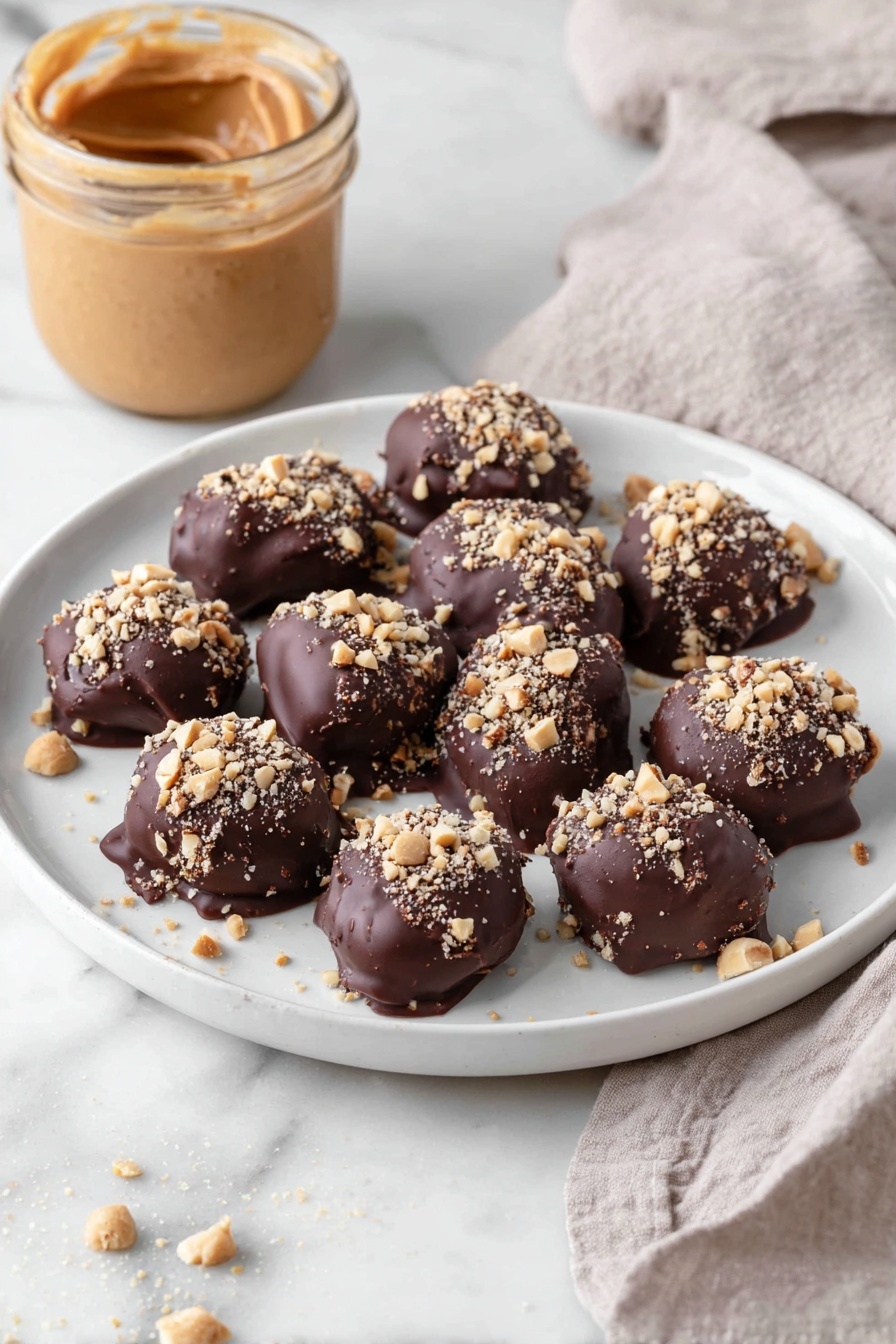 Chocolate-Dipped Peanut Butter Stuffed Dates, peanut butter stuffed dates, chocolate date snacks, healthy date treats, easy dessert bites - A white plate holds eleven bite-sized treats, each covered in a thick, dark brown chocolate layer with a slightly glossy and smooth texture. On top of each piece, there is a sprinkling of small, light tan chopped nuts adding a rough, crunchy texture. The treats are arranged loosely close to each other in the center of the plate. In the background, there is an open jar filled with smooth, creamy peanut butter in a light brown shade, and a light beige cloth with a soft, woven texture lies nearby on a white marbled surface. Photo taken with an iphone --ar 2:3 --v 7