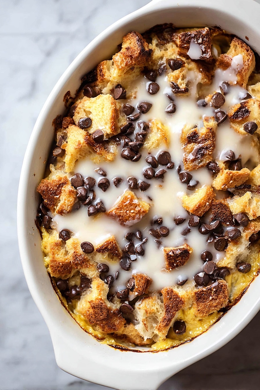 Tres Leches Bread Pudding with Chocolate Chips, tres leches bread pudding, bread pudding with chocolate chips, creamy tres leches dessert, indulgent bread pudding recipe - A white oval dish filled with a baked dessert featuring a rough top layer of golden brown bread chunks mixed with melted dark chocolate chips scattered evenly. Below this, a creamy, slightly crispy, yellow layer is visible, soaked with a white glaze drizzled across the top, adding a shiny texture. The edges of the dish show browned and slightly caramelized spots, giving a crunchy look to the dessert. The dish rests on a white marbled surface. photo taken with an iphone --ar 2:3 --v 7