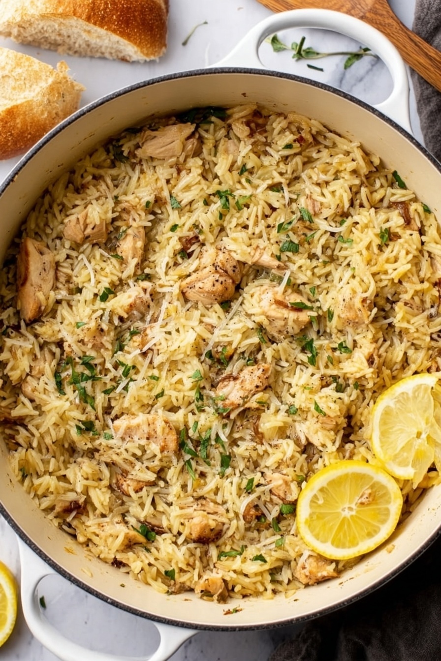 Lemon Chicken and Orzo, Lemon Chicken and Orzo recipe, easy lemon chicken with orzo, quick lemon chicken skillet, healthy lemon chicken dinner - A white pot filled to the top with cooked yellowish rice mixed with small pieces of light-brown cooked chicken, scattered with thin green herb leaves and a sprinkle of grated cheese or seasoning on top, with two thin lemon slices resting near the edge of the pot. The pot is placed on a white marbled surface with a piece of bread in the top left corner and a woman's hand in the lower left corner holding a utensil. photo taken with an iphone --ar 2:3 --v 7