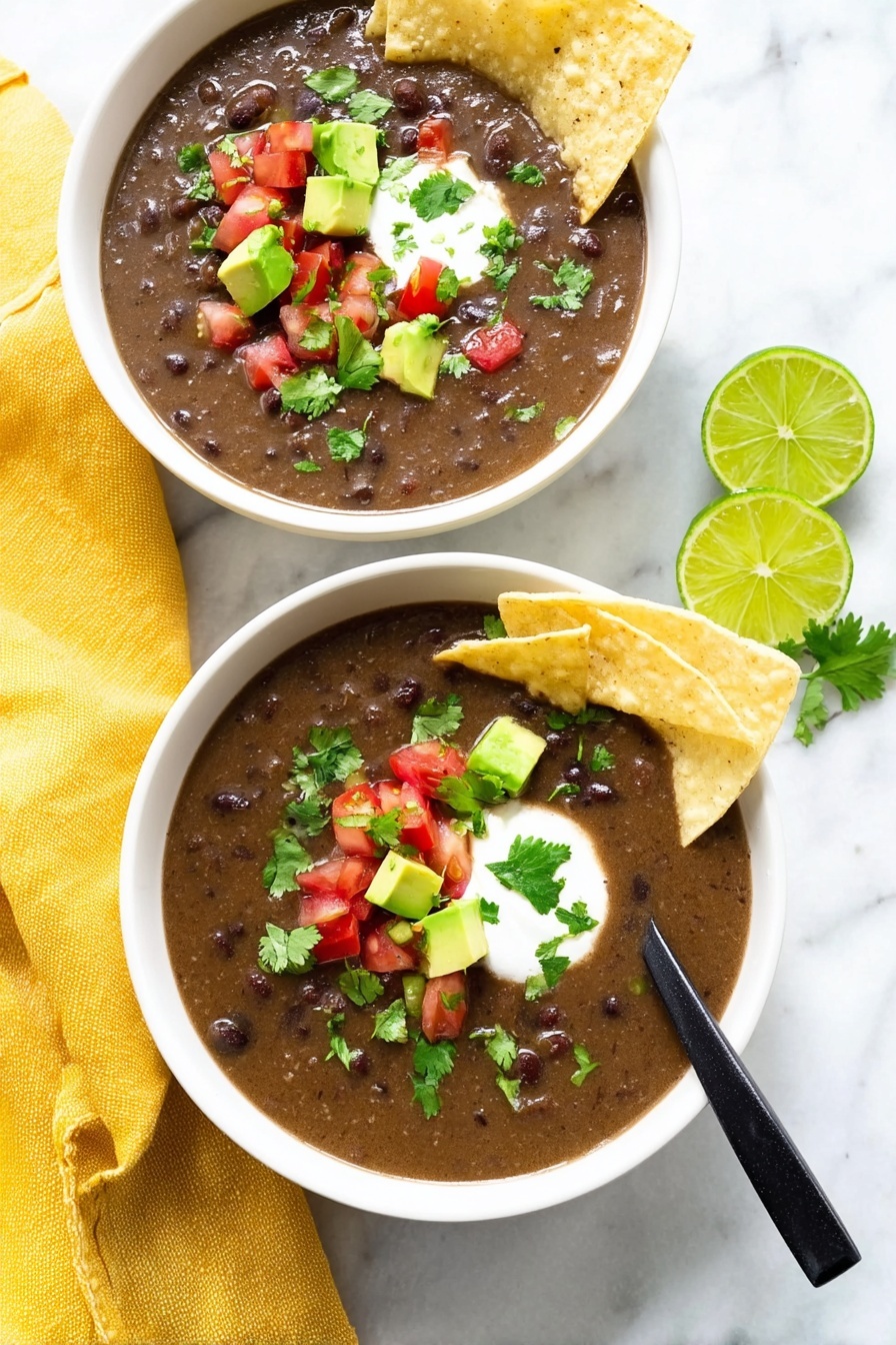 Vegan Black Bean Soup, vegan black bean soup savory dish, hearty vegan soup recipe, plant-based black bean soup, easy vegan soup ideas - The image shows two white bowls filled with dark brown bean soup that has a thick texture. Each bowl has two light beige tortilla chips placed on the side, slightly dipped into the soup. On top of the soup, there are small cubes of bright green avocado, small pieces of red tomato, chopped green cilantro, and a dollop of white cream in the center. One bowl has a black spoon resting inside. The bowls sit on a white marbled surface with a yellow cloth napkin next to one bowl and two lime wedges nearby. The scene is bright and clean. Photo taken with an iphone --ar 2:3 --v 7