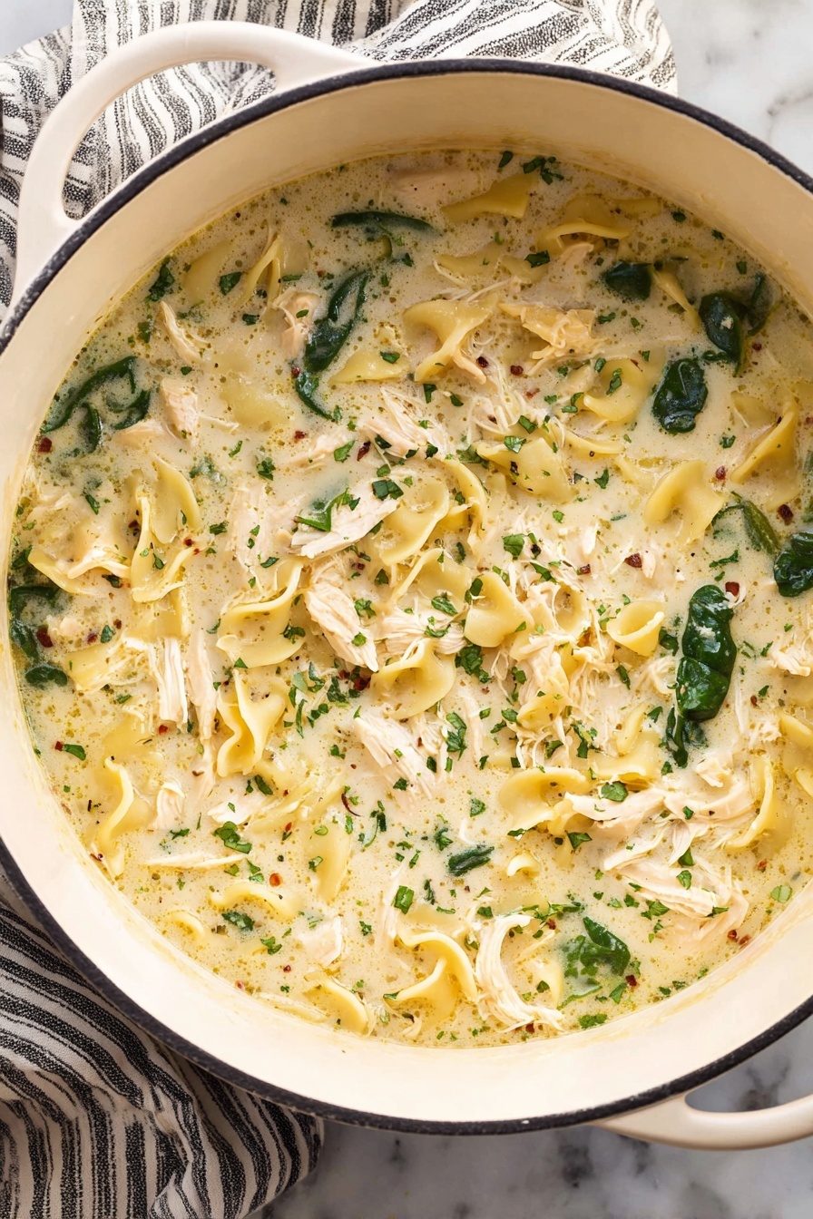 White Lasagna Soup, White Lasagna Soup recipe, creamy lasagna soup, easy lasagna soup, comforting chicken lasagna soup - A white pot filled with creamy soup that has three main layers: shredded white chicken pieces spread evenly, dark green spinach leaves scattered throughout, and curly, pale yellow pasta floating in a thick, light cream broth with small herbs sprinkled all over. The pot is placed on a white marbled surface with a striped cloth under one side. Photo taken with an iphone --ar 2:3 --v 7