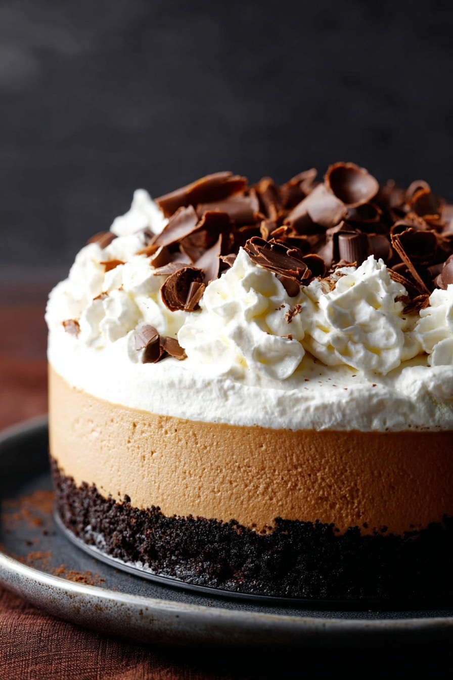 Chocolate Pumpkin Cheesecake with Bourbon Whipped Cream, fall pumpkin cheesecake, bourbon whipped cream dessert, autumn holiday cheesecake, easy pumpkin spice dessert - A three-layer dessert is shown, starting with a dark crumbly chocolate base at the bottom, followed by a thick smooth light brown creamy layer in the middle, topped with a generous fluffy white whipped cream layer. The whipped cream is decorated with scattered dark brown curled chocolate pieces. The dessert sits on a dark surface with a soft dark background. photo taken with an iphone --ar 2:3 --v 7