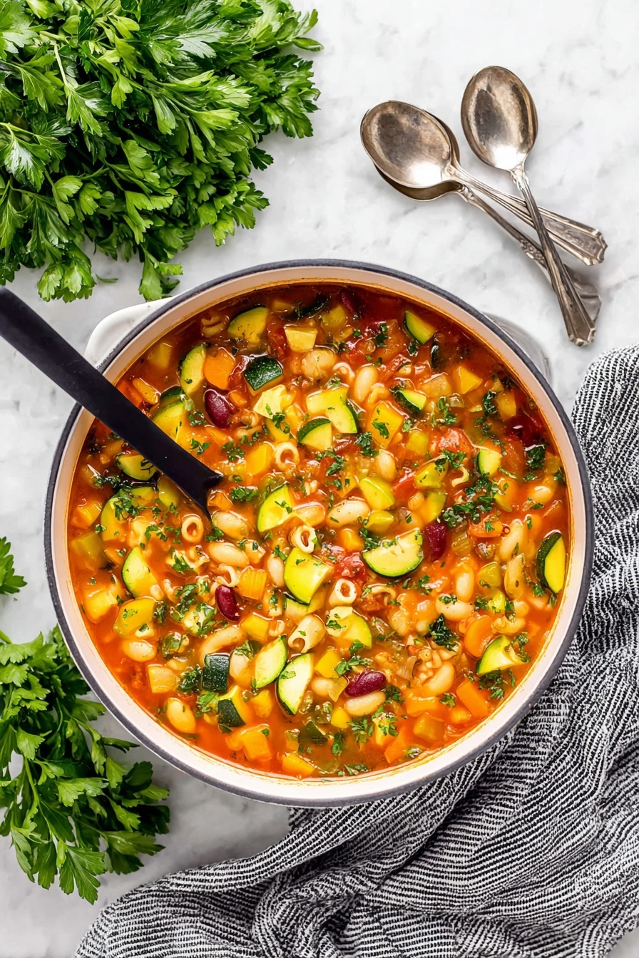 Easy Minestrone Soup, hearty Italian vegetable soup, quick vegetable soup recipe, healthy minestrone, comforting veggie soup - A close-up of a white pot filled with colorful minestrone soup, showing about five layers of ingredients in a light red broth. The soup contains small pasta shells, dark red kidney beans, orange carrot cubes, yellow and green zucchini slices, green celery pieces, and diced tomatoes. A ladle is lifting a scoop of soup with a mix of these ingredients, showcasing their textures and colors. The background has a white marbled texture with some green herb leaves visible around the pot. Photo taken with an iphone --ar 2:3 --v 7