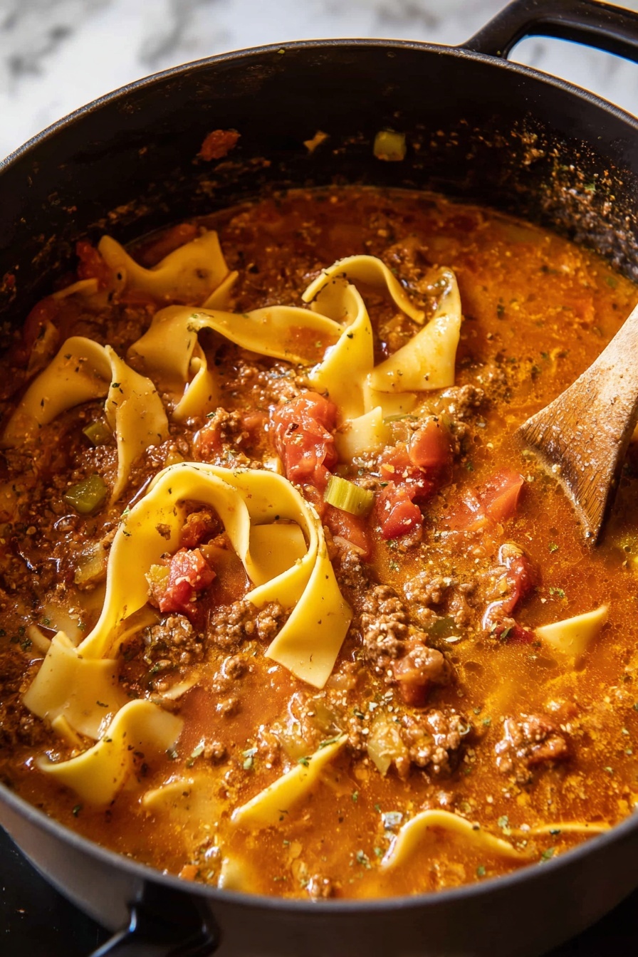 Spicy Lasagna Soup, Italian soup recipes, easy weeknight dinners, cheesy soup recipes, spicy sausage soup - A black pot filled with thick lasagna soup showing several wide, flat, yellow pasta sheets, some curled and some straight, floating on a rich, chunky tomato-based broth with visible pieces of ground meat, diced red tomatoes, and bits of green celery. The soup has a slightly oily, speckled surface with herbs and spices, and steam rises gently from the hot mixture. A wooden spoon is partly submerged on the right side, stirring the soup. The pot is positioned against a white marbled background. photo taken with an iphone --ar 2:3 --v 7