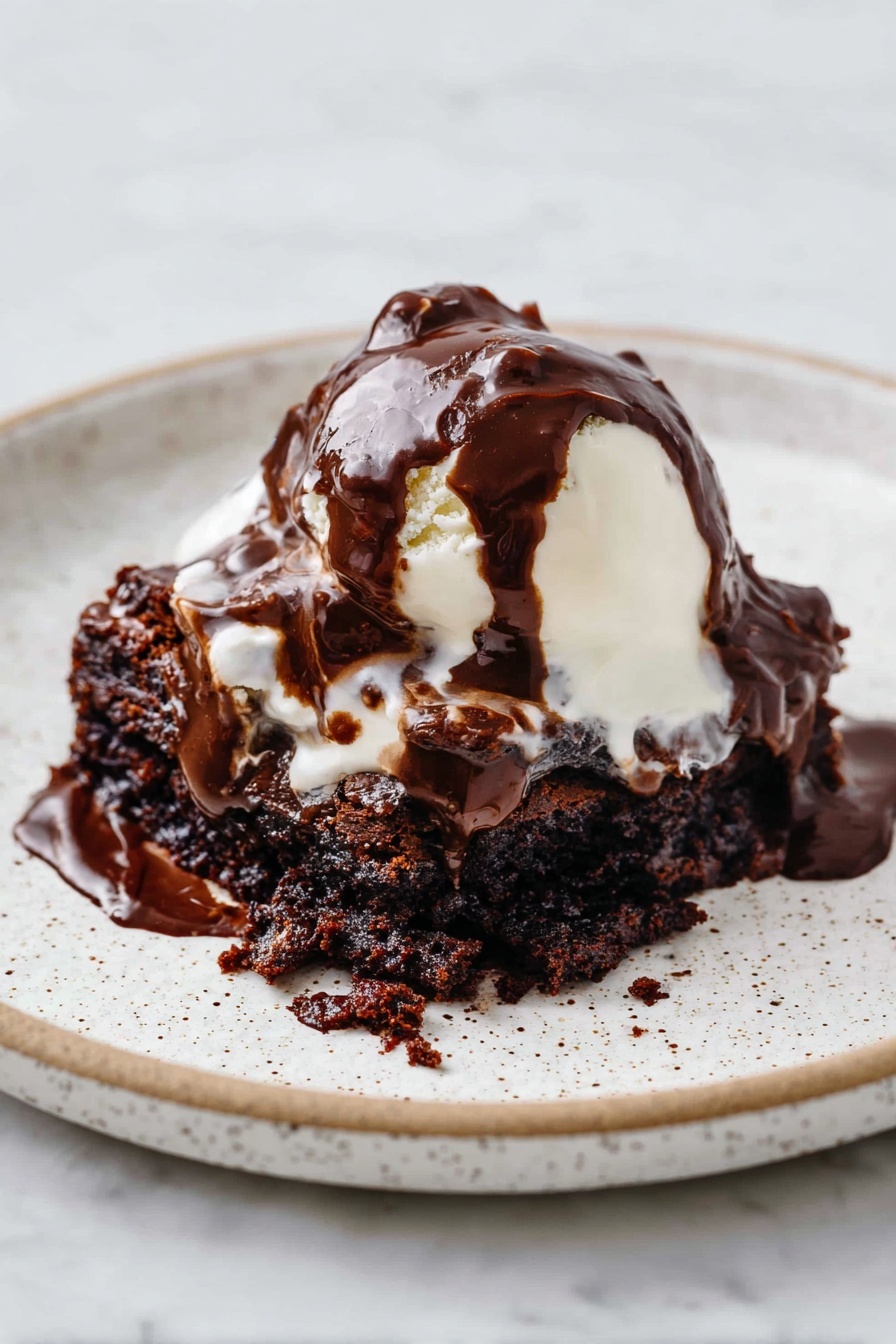 Decadent Hot Fudge Cake, hot fudge cake recipe, gooey chocolate cake, easy chocolate dessert, indulgent chocolate cake - A white speckled plate holds a dessert with three main layers. The bottom layer is a dark brown, moist chocolate cake with a rough, crumbly texture. On top of this is a soft, white scoop of melting ice cream that is smooth and creamy. The top layer is thick, glossy dark chocolate sauce, generously poured over the ice cream and cake, flowing and blending into the layers below. The plate sits on a white marbled surface. photo taken with an iphone --ar 2:3 --v 7