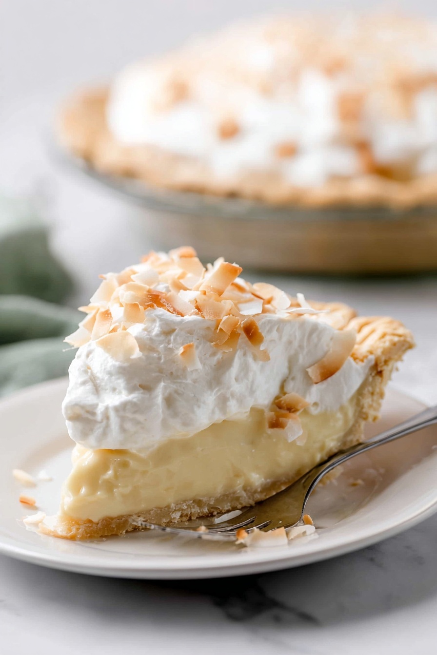 Homemade Coconut Cream Pie, coconut cream pie, tropical dessert recipes, coconut custard pie, flaky crust coconut pie - A slice of pie is shown on a white plate, with three clear layers. The bottom layer is a light golden crust with a slightly crumbly texture. The middle layer is thick and creamy, pale yellow in color, smooth and soft looking. The top layer is white whipped cream, fluffy, covered with toasted coconut flakes that are light brown and white, scattered unevenly. The pie is on a white marbled surface, and in the background, the rest of the pie is visible in a clear pie dish. A silver fork with text is placed beside the slice on the plate. photo taken with an iphone --ar 2:3 --v 7
