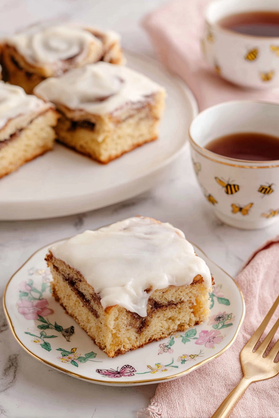 Cinnamon Roll Cake, easy cinnamon roll cake, moist cinnamon cake, cinnamon swirl dessert, quick cinnamon roll treat - The image shows three square pieces of cinnamon roll cake with a light brown base and a visible swirl of darker cinnamon filling inside. Each piece is topped with a thick, creamy white icing that spreads unevenly on top. The pieces sit on white plates with delicate gold edges and small floral designs. A white teacup with a gold line on the rim and small floral pattern holds dark brown tea, positioned beside one of the plates. A gold fork rests on a soft pink napkin near the front plate. The background is a white marbled surface, and a tray with more pieces is visible in the back. Photo taken with an iphone --ar 2:3 --v 7