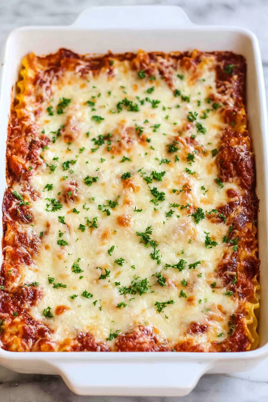 Cheesy Beef Lasagna Roll-Ups, easy baked lasagna roll-ups, cheesy beef pasta, homemade lasagna recipes, family-friendly dinner - A white rectangular baking dish filled with a layered lasagna. The top layer is melted cheese with golden brown spots and sprinkled with small green parsley pieces. The layer underneath shows hints of a rich red tomato sauce and pasta edges peeking through. The dish is placed on a white marbled surface. photo taken with an iphone --ar 2:3 --v 7