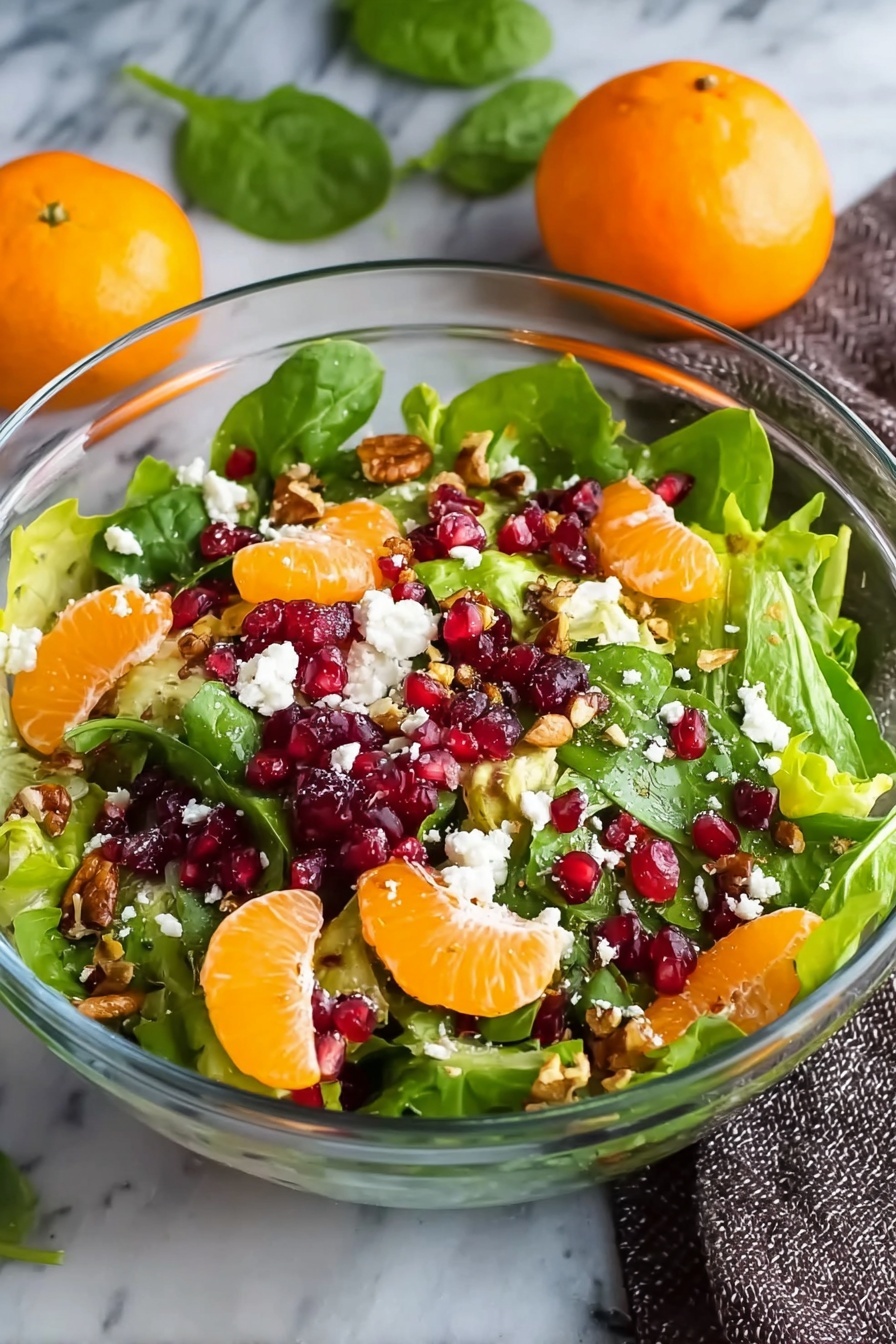 Winter Citrus Salad with Pomegranate and Feta, winter citrus salad, festive fruit salad, healthy winter salad, citrus and feta appetizer - A clear glass bowl filled with a colorful salad, showing a mix of green leafy spinach and lettuce as the base layer, topped with bright orange mandarin slices scattered evenly, followed by deep red pomegranate seeds sprinkled throughout, and small white crumbles of cheese spread on top. Bits of brown nuts add texture and are scattered on the salad. The bowl is placed on a white marbled surface, with two whole mandarins and green leaves blurred in the background, and a gray textured cloth to the right, photo taken with an iphone --ar 2:3 --v 7
