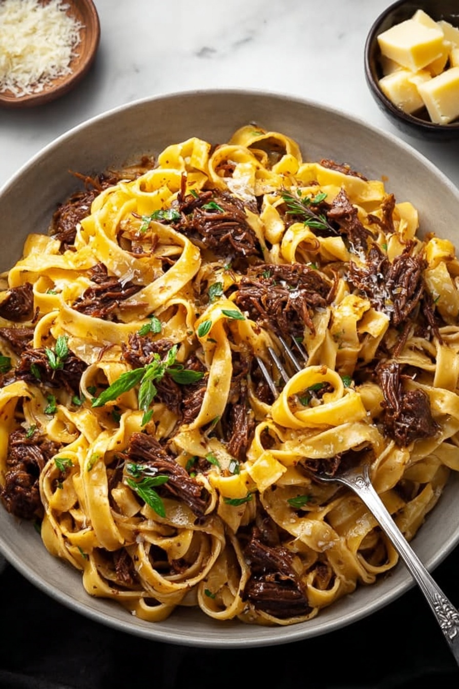 Short Rib Ragu Pasta, hearty beef pasta, slow-cooked short rib dish, comforting Italian pasta, flavorful beef ragu - A large white bowl filled with a generous serving of tagliatelle pasta mixed with shredded dark brown meat pieces. The pasta is light golden yellow with a slight shine, entwined among the tender meat chunks. Fresh green herb leaves are scattered on top, adding a touch of color and freshness. A small metal fork is placed inside the bowl, partly twirling some pasta and meat. In the background, a small bowl holds chunks of light yellow cheese, and everything is set against a white marbled surface. Photo taken with an iphone --ar 2:3 --v 7