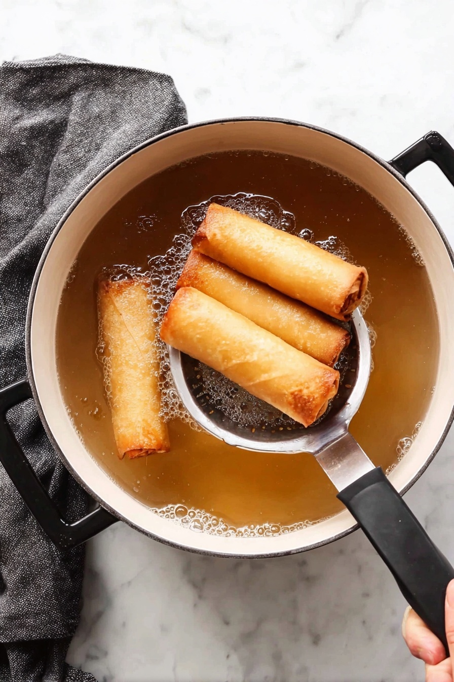 Vegetable Sweet Potato Spring Rolls, healthy spring rolls, veggie spring roll recipe, crispy vegetable rolls, vegan spring rolls - A white pot with black handles is filled with light brown hot oil, frying four golden spring rolls that are crispy and smooth on the outside. A stainless steel slotted spoon holds three spring rolls gently above the oil while a woman's hand holds the pot’s black handle. The white marbled surface beneath has a folded dark gray towel on the left side. The scene shows the texture of the cooked spring rolls with a small amount of bubbles around them in the oil photo taken with an iphone --ar 2:3 --v 7