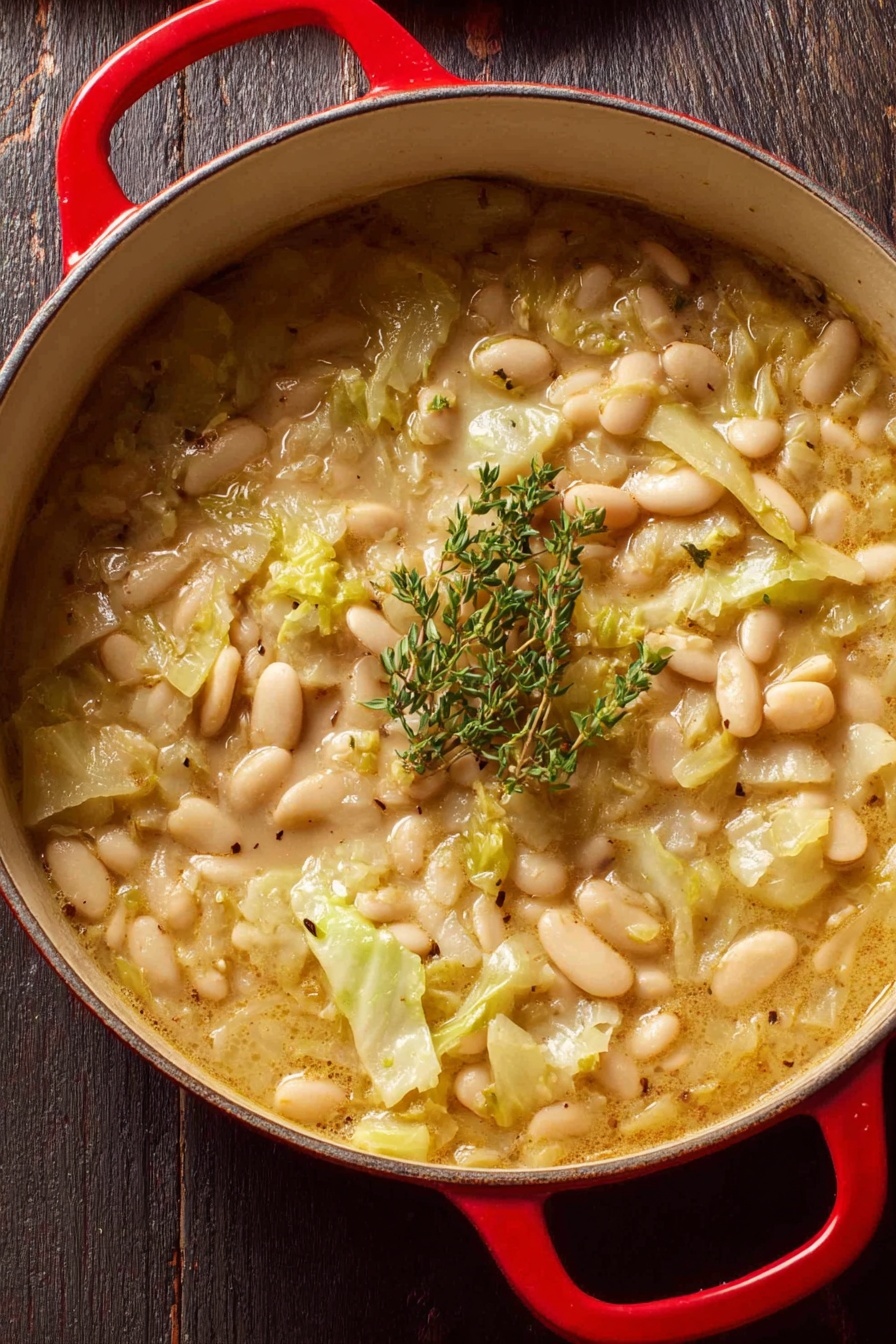 Creamy Butter Bean and Leek Skillet, creamy leek and bean dish, easy vegetarian skillet recipe, comforting leek and beans meal, quick plant-based dinner - A close-up view of a red pot filled with a thick stew made of white beans and chopped light green cabbage in a creamy broth. The stew shows soft textures with some beans floating on top mixed with pieces of cabbage, and it is garnished with a small bunch of fresh green thyme placed in the center. The pot is resting on a dark wooden surface. photo taken with an iphone --ar 2:3 --v 7