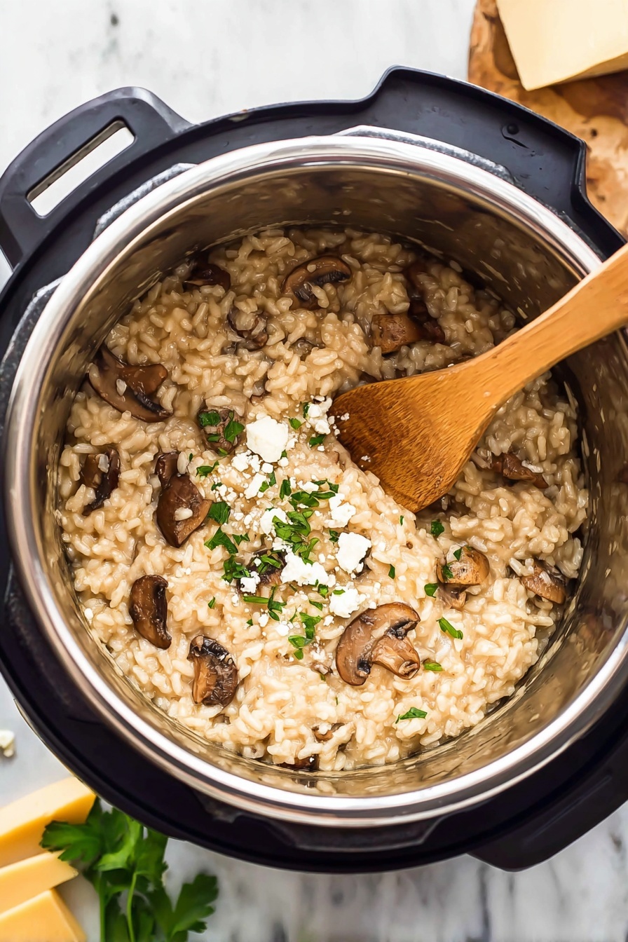 Pressure Cooker Mushroom Risotto, Mushroom Risotto in Pressure Cooker, Easy Mushroom Risotto Recipe, Creamy Mushroom Risotto, Fast Risotto with Mushrooms - The image shows a close-up of a mushroom risotto inside a shiny stainless steel pot of a kitchen pressure cooker. The risotto is creamy with light beige rice mixed with pieces of cooked brown mushrooms spread evenly throughout. Some small bits of chopped green herbs and crumbled white cheese are sprinkled on top, giving a fresh and textured look. A light brown wooden spoon rests inside the risotto, leaning against the side of the pot. The pot sits on a white marbled surface, with blurred green leaves and chunks of yellow cheese in the background. Photo taken with an iphone --ar 2:3 --v 7