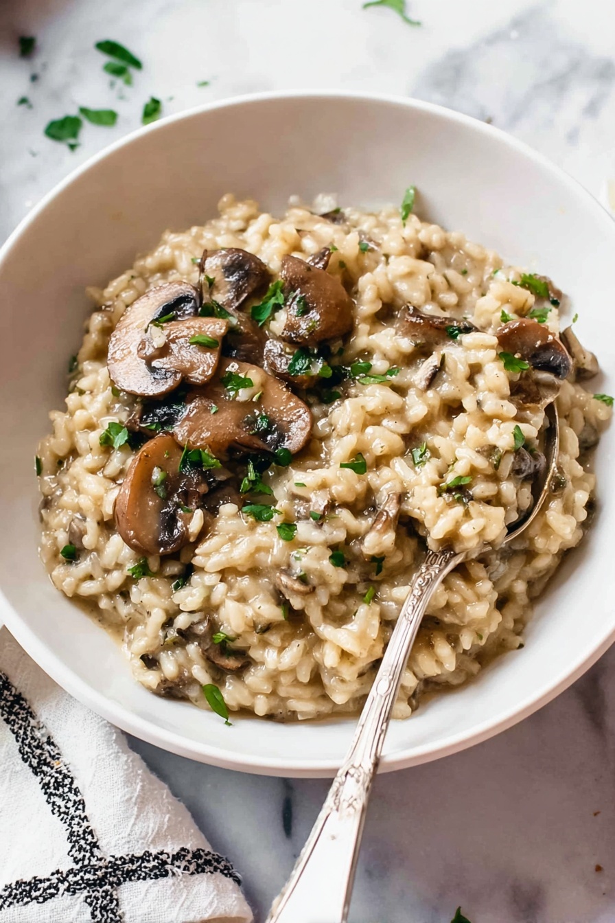 Pressure Cooker Mushroom Risotto, Mushroom Risotto in Pressure Cooker, Easy Mushroom Risotto Recipe, Creamy Mushroom Risotto, Fast Risotto with Mushrooms - A white bowl filled with creamy mushroom risotto. The risotto has a thick, soft texture with plump, tender rice grains mixed with sliced brown mushrooms. Small pieces of green herbs are sprinkled on top, adding color contrast. A silver spoon is partially dipped into the risotto, resting near the edge of the bowl. The bowl sits on a white marbled surface with part of a white and black patterned cloth visible in the background. Photo taken with an iphone --ar 2:3 --v 7