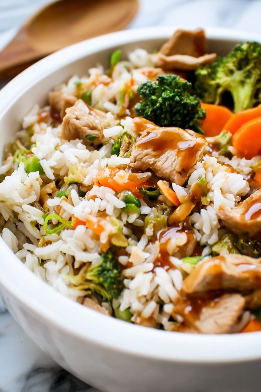 Teriyaki Chicken Casserole with Vegetables, healthy teriyaki chicken bake, easy chicken casserole recipe, flavorful vegetable chicken bake, quick weeknight dinner ideas - The image shows a white bowl filled with a colorful stir-fry dish on a white marbled surface. The dish has three main layers: at the bottom, there is a layer of cooked rice with a light brown color and fluffy texture. The middle layer contains a mix of bright orange baby carrots, green snap peas, and small broccoli florets, giving the dish a fresh and vibrant look. The top layer is a light drizzle of dark brown sauce covering parts of the rice and vegetables, adding a shiny finish. The overall look is warm and inviting, with a mix of soft and crisp textures visible. Photo taken with an iphone --ar 2:3 --v 7