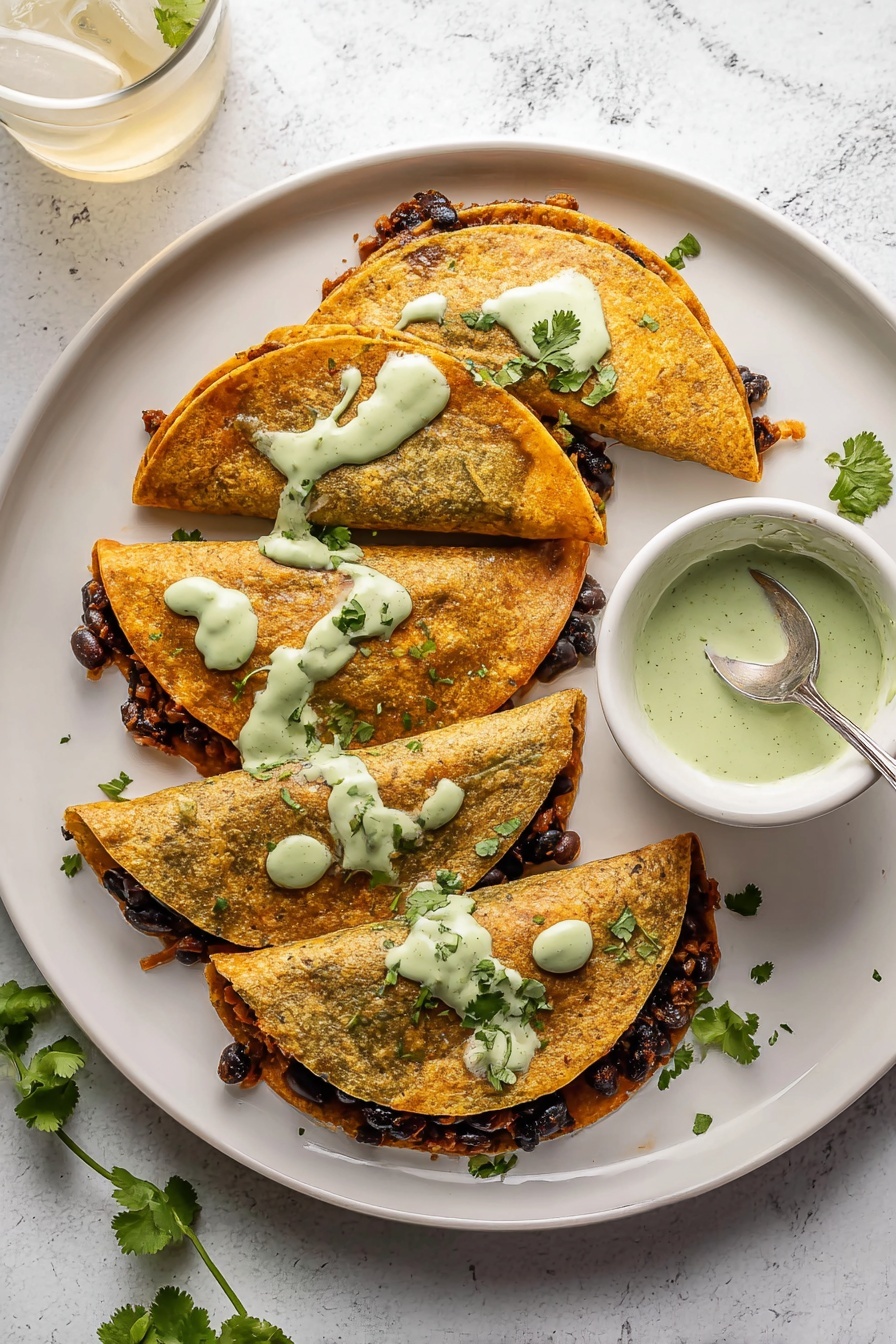 Crispy Ground Turkey Tacos with Avocado Sauce, ground turkey taco recipe, healthy ground turkey tacos, easy taco dinner ideas, avocado sauce for tacos - The image shows four folded golden-brown tortillas on a white plate with a white marbled surface background. Each tortilla is filled with a dark layer of what looks like cooked black beans mixed with a brown filling, peeking out slightly from the open edges. There are light green creamy sauce dollops spread unevenly over the top of the tortillas with some dripping down the sides. Fresh green cilantro leaves are scattered around the plate and a small white bowl with more of the light green sauce and a spoon inside it sits on the right side. A glass with ice and a light-colored drink is at the top left corner. Photo taken with an iphone --ar 2:3 --v 7