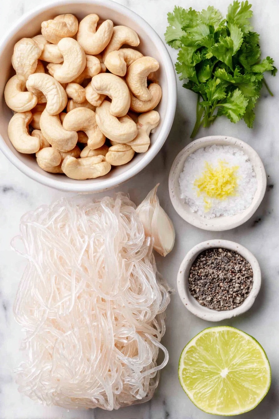 Vegan Cilantro Lime Noodles, vegan noodle recipes, dairy-free cilantro lime pasta, quick vegan dinner ideas, healthy vegan noodle dishes - Flat lay of raw cashews in a small pile, a small handful of bright green cilantro sprigs, two whole uncracked garlic cloves, a whole fresh lime with one half cut to show the juicy interior and scattered lime zest, a small white ceramic bowl filled with clear water, a small white ceramic bowl containing coarse salt, a small white ceramic bowl with cracked black peppercorns, and a neat bundle of tofu shirataki spaghetti shaped noodles, all arranged in perfect symmetry on a clean white marble surface, soft natural light, photo taken with an iPhone, professional food photography style, fresh ingredients, white ceramic bowls, no bottles, no duplicates, no utensils, no packaging --ar 2:3 --v 7 --p m7354615311229779997