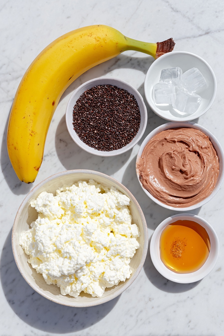 Chocolate Peanut Butter Protein Smoothie, healthy chocolate peanut butter smoothie, high-protein dessert smoothie, easy chocolate peanut butter smoothie recipe, no protein powder smoothie - Flat lay of a ripe yellow banana, a small white ceramic bowl of glossy black chia seeds, a few irregular ice cubes scattered naturally, a white ceramic bowl filled with creamy white cottage cheese, a small white bowl of rich brown cocoa powder, a small white bowl holding fine light tan peanut butter powder, a small white bowl of fresh milk, and a small white bowl of golden amber maple syrup, all arranged in perfect symmetry and natural proportions, placed on a clean white marble surface, soft natural light, photo taken with an iPhone, professional food photography style, fresh ingredients, white ceramic bowls, no bottles, no duplicates, no utensils, no packaging --ar 2:3 --v 7 --p m7354615311229779997